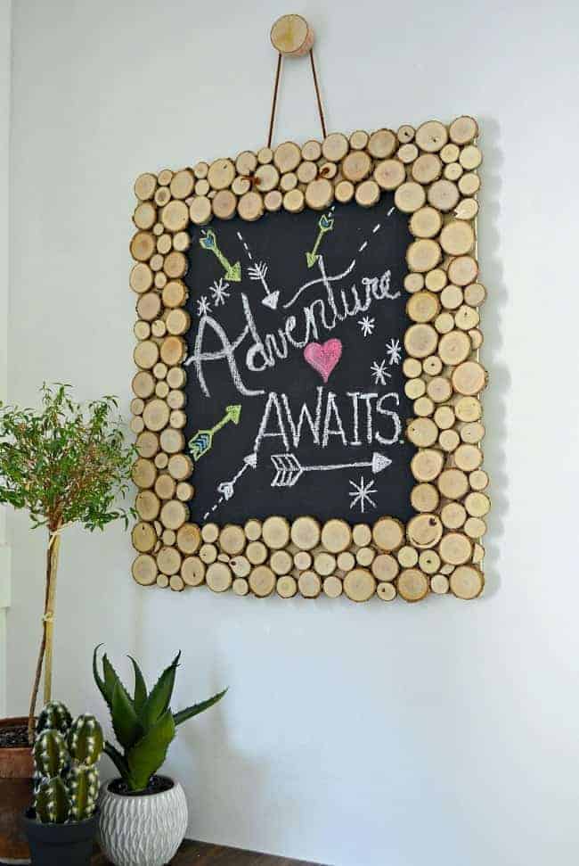 Rustic Wood Slice Chalkboard hanging on white wall with 3 green plants sitting on a wood countertop