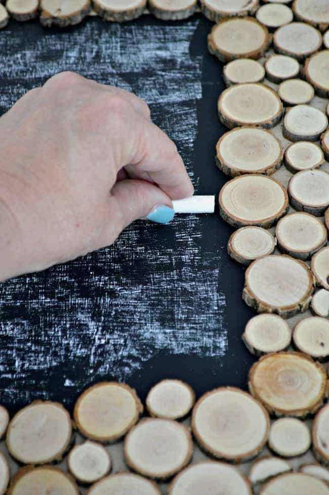 seasoning the chalkboard with chalk while making a rustic wood slice chalkboard