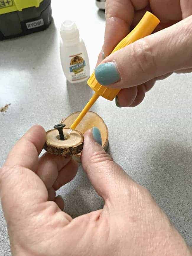 brushing glue onto a wood round while making a rustic wood slice chalkboard