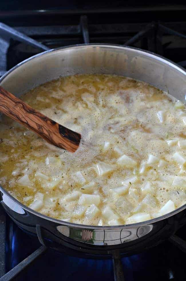 Easy New England clam chowder cooking in big metal pot on stove