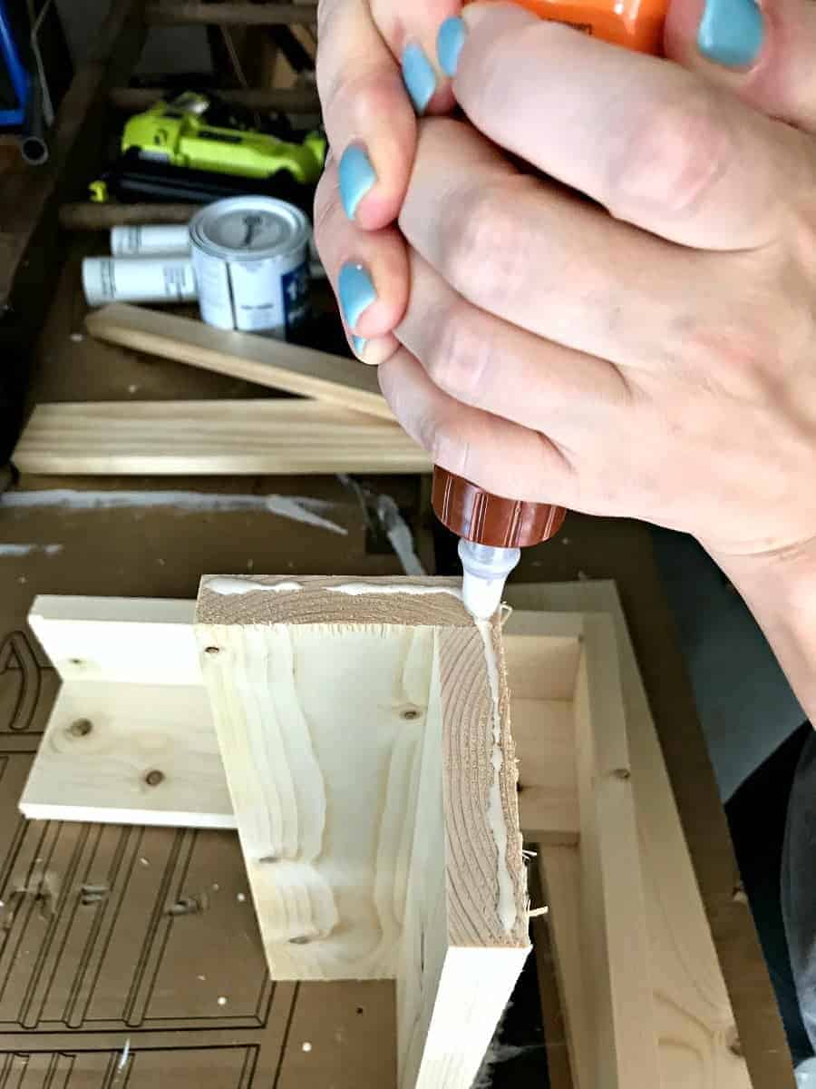 applying wood glue to pine shelf while making a wall mounted coat rack