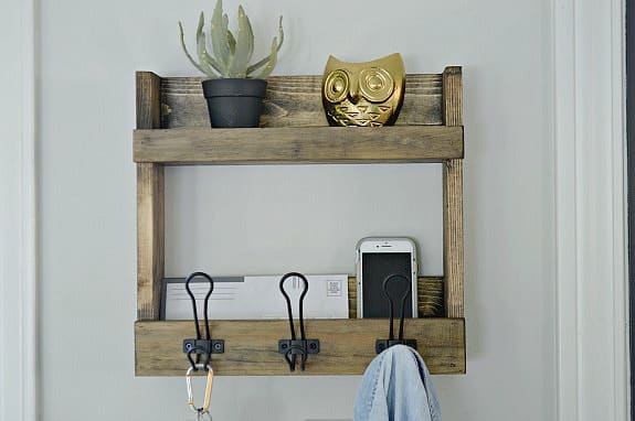 DIY coat rack with storage shelves hanging on wall with plant, owl and keys hanging on it