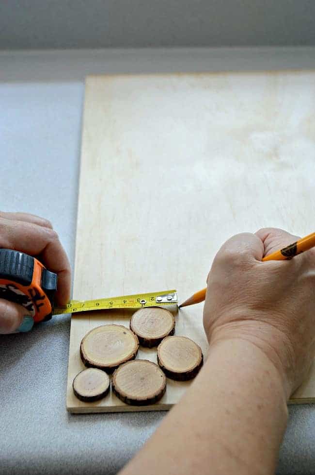 measuring border on underlayment with a measuring tape to make a rustic wood slice chalkboard