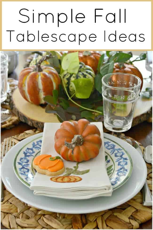 Simple Fall Tablescape Ideas Using Blue, White and Orange Pinterest Image table setting with orange pumpkin on cream embroidered napkin with a pumpkin shaped cookie for a Simple Fall Tablescape Ideas post