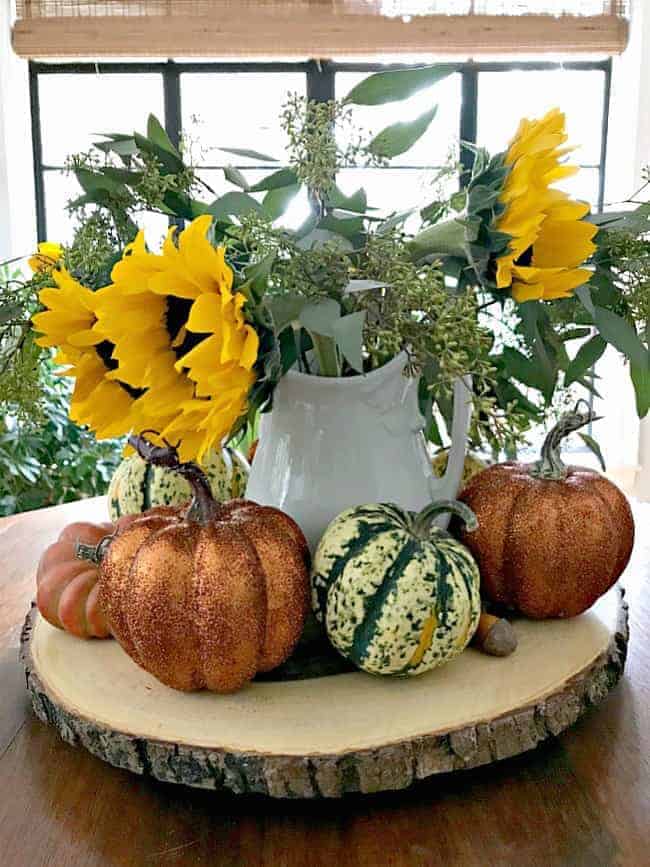pitcher of sunflowers with glitter pumpkins in front