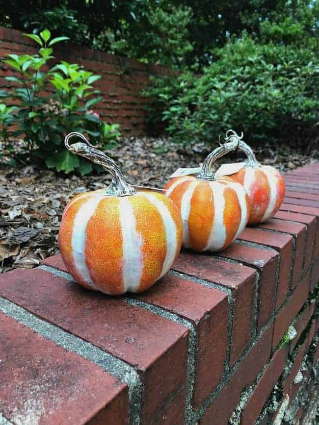 3 faux pumpkins sitting on a brick wall that will be turned into DIY glitter pumpkins