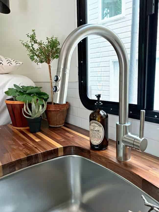 new kitchen faucet and bottle of hand soap on butcher block countertop for rv remodel update