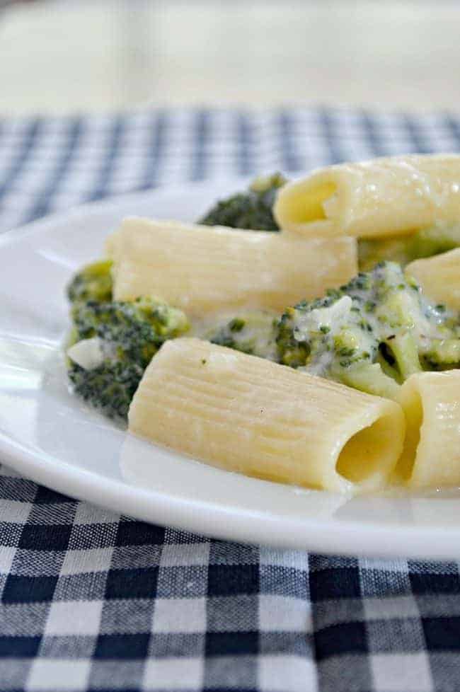 cheesy skinny broccoli alfredo on white plate with a blue checked napkin
