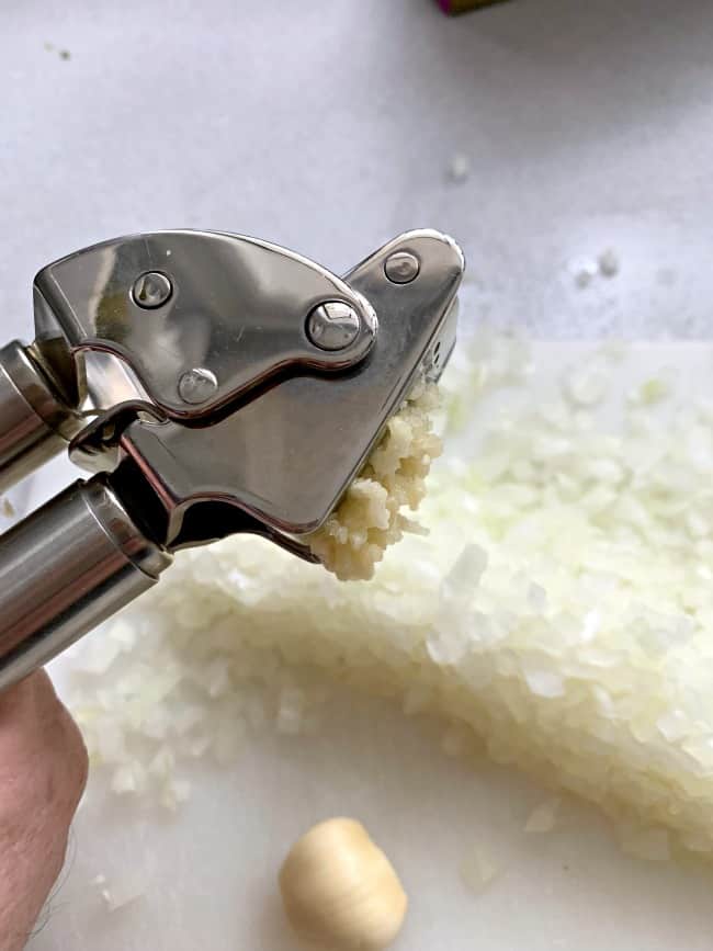 mincing garlic clove in garlic press