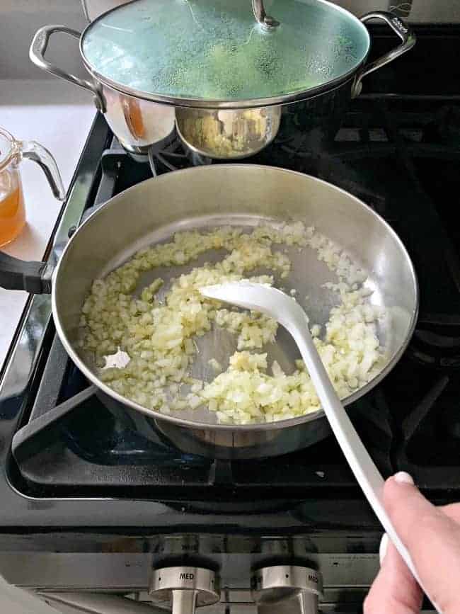 stirring saucepan on stove with garlic and onions