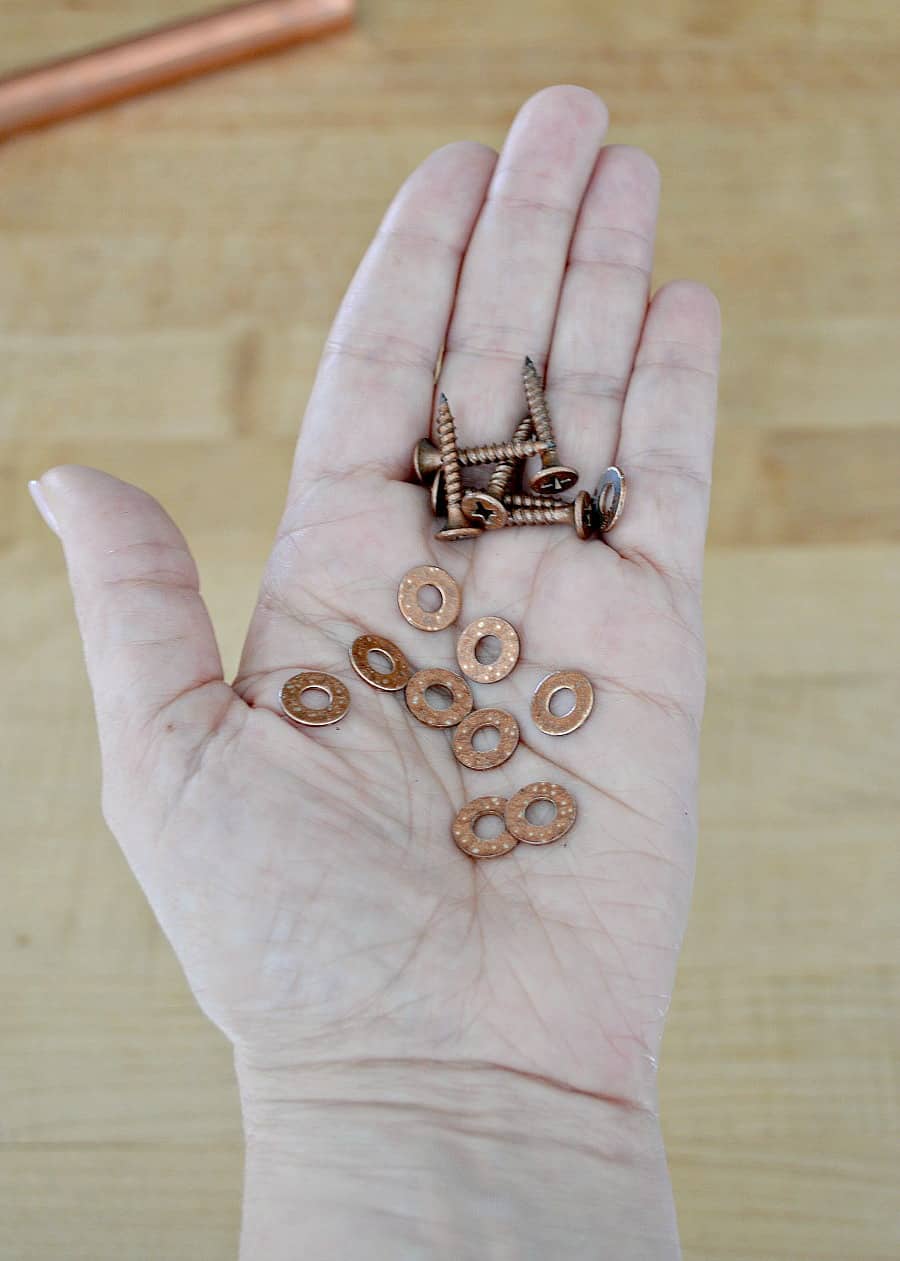 copper painted washers and screws in the palm of a hand