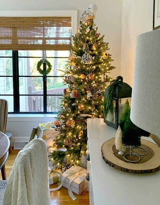 A Rustic Christmas Tree in a dining room corner with gifts underneath 