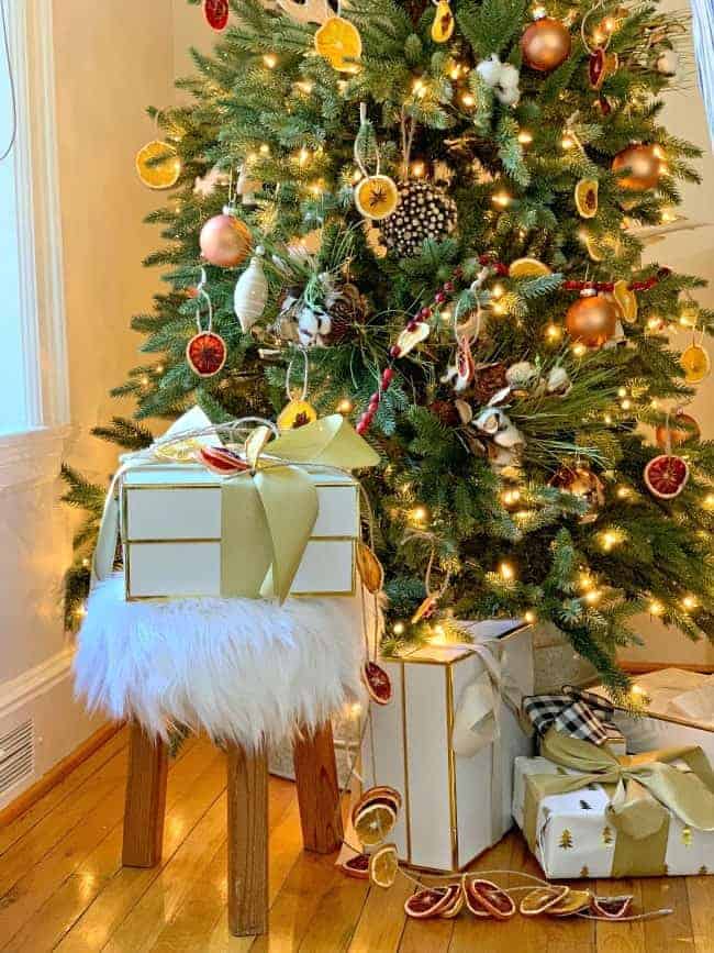 A Rustic Christmas Tree with a fur covered stool under it and wrapped gifts