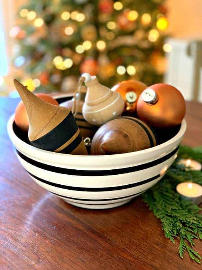 black and cream bowl on wood table with wood ornaments and burnt orange glass balls