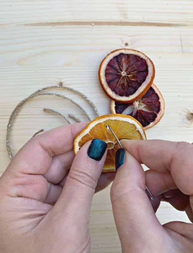 using needle to poke hole in dried orange slice ornament