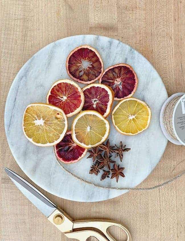 overview of dried orange slices on marble cutting board with scissors and twine