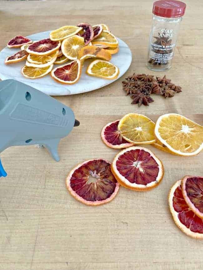 dried orange slices, star anise and hot glue gun on a butcher block countertop