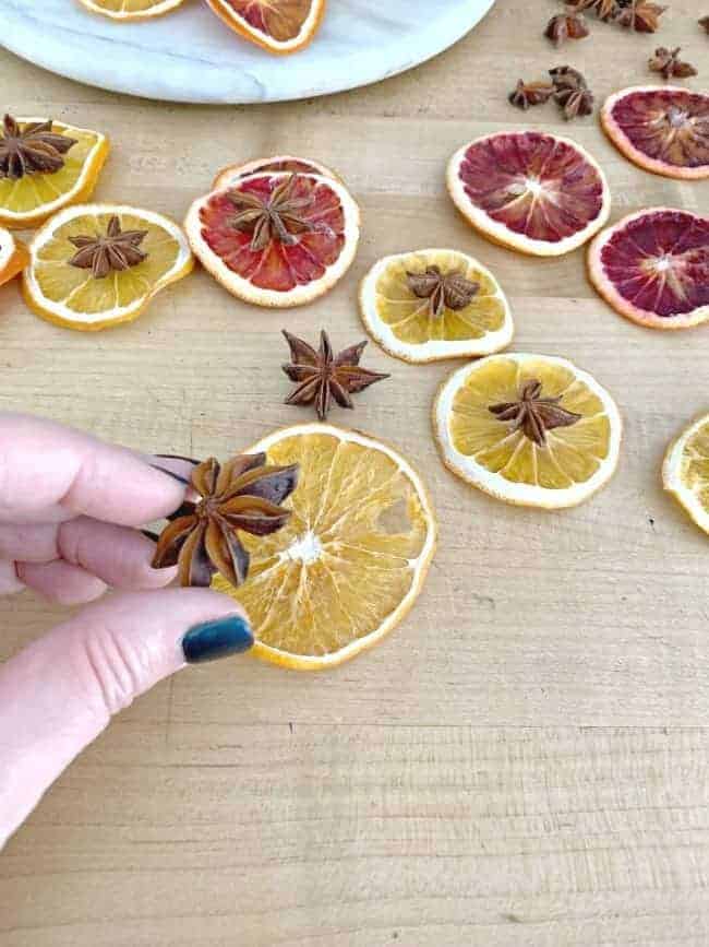 glueing star anise on dried orange slice with more dried orange slices scattered around