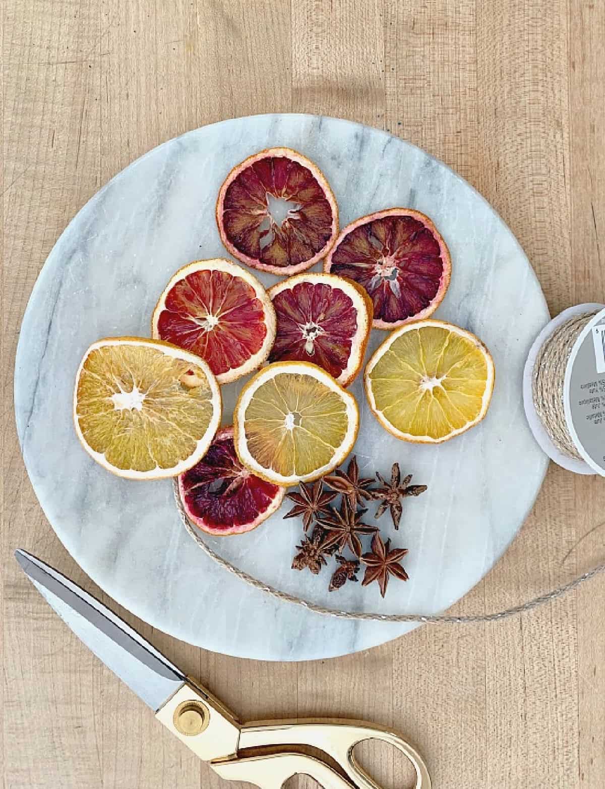 DIY Dried Orange Slice Ornaments picture dried 0range slices, twine and scissors on tray