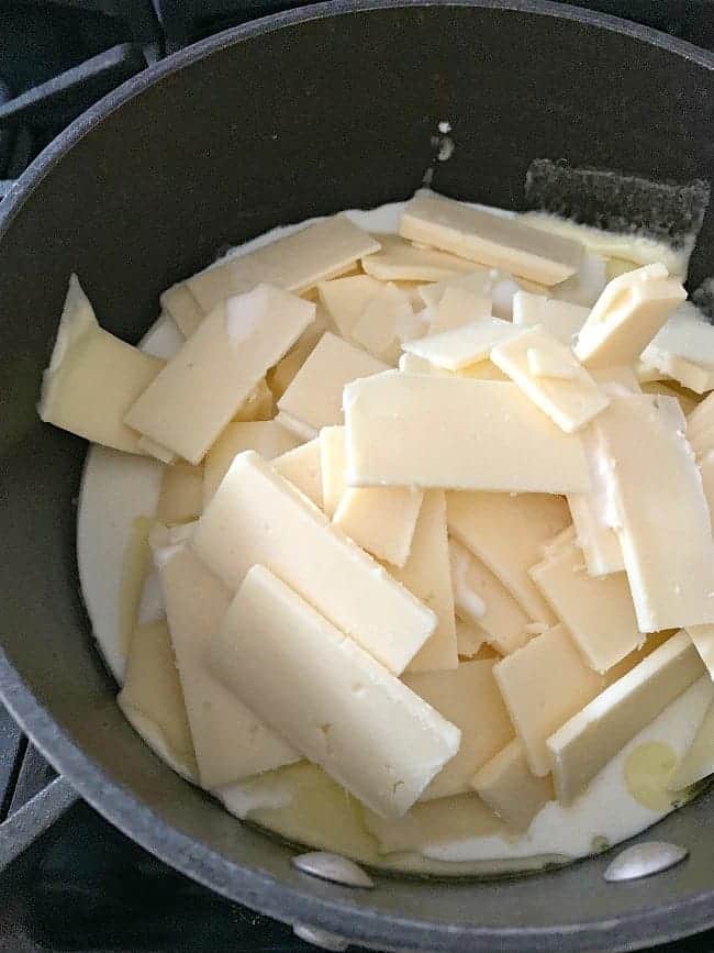 sliced white cheese and milk in saucepan on stove