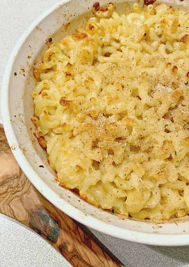 baked homemade cheesy mac and cheese in baking dish with wooden spoon next to it