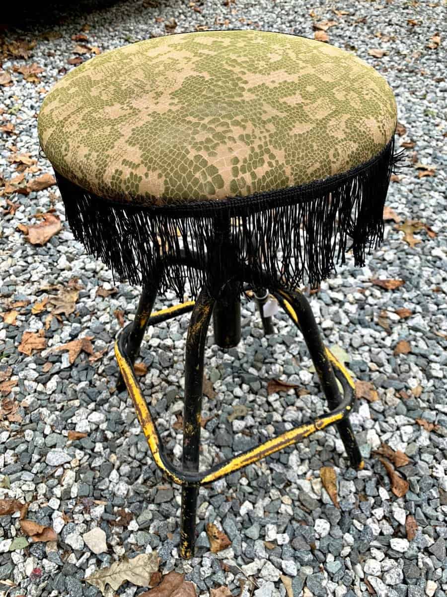 old thrifted metal stool with black fringe on seat