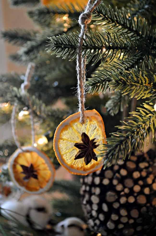 DIY dried orange slice ornaments hanging in a Christmas tree with a jute ribbon