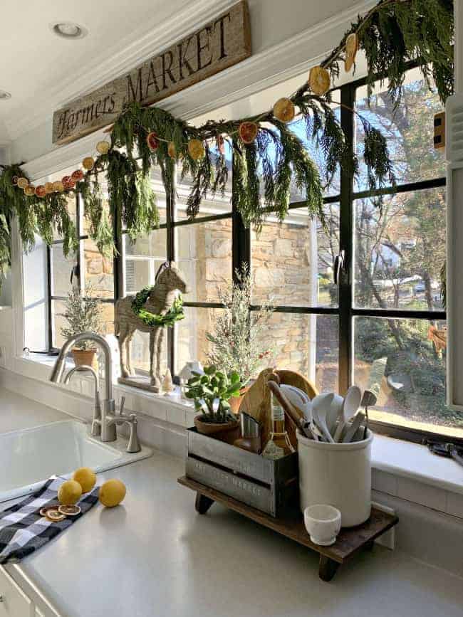 fresh greens and an orange slice garland hanging on a large kitchen window