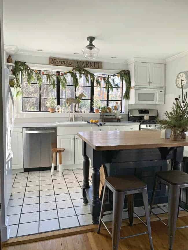 aa view of a small white kitchen with fresh greens hanging on it