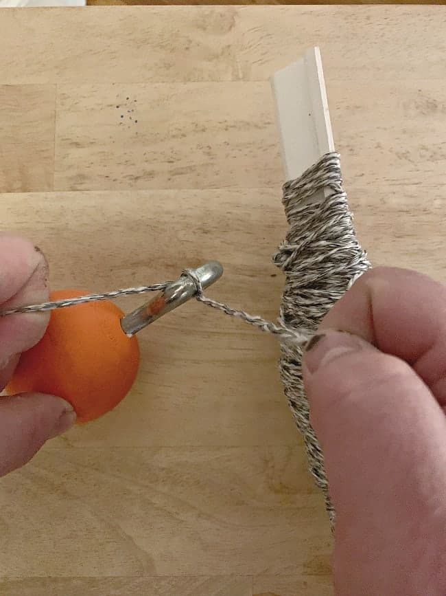 string tied to orange lacrosse ball with an eye bolt in it