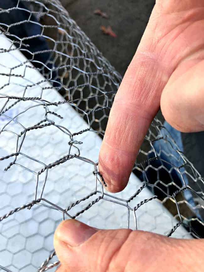 bending tabs in cut chicken wire to make DIY lighted chicken wire Christmas balls