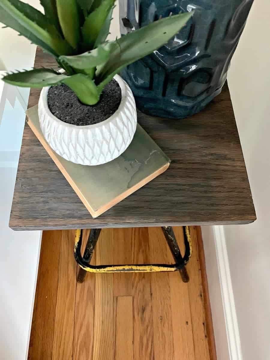 top view of DIY nightstand with a blue lamp and potted plant next to platform bed 