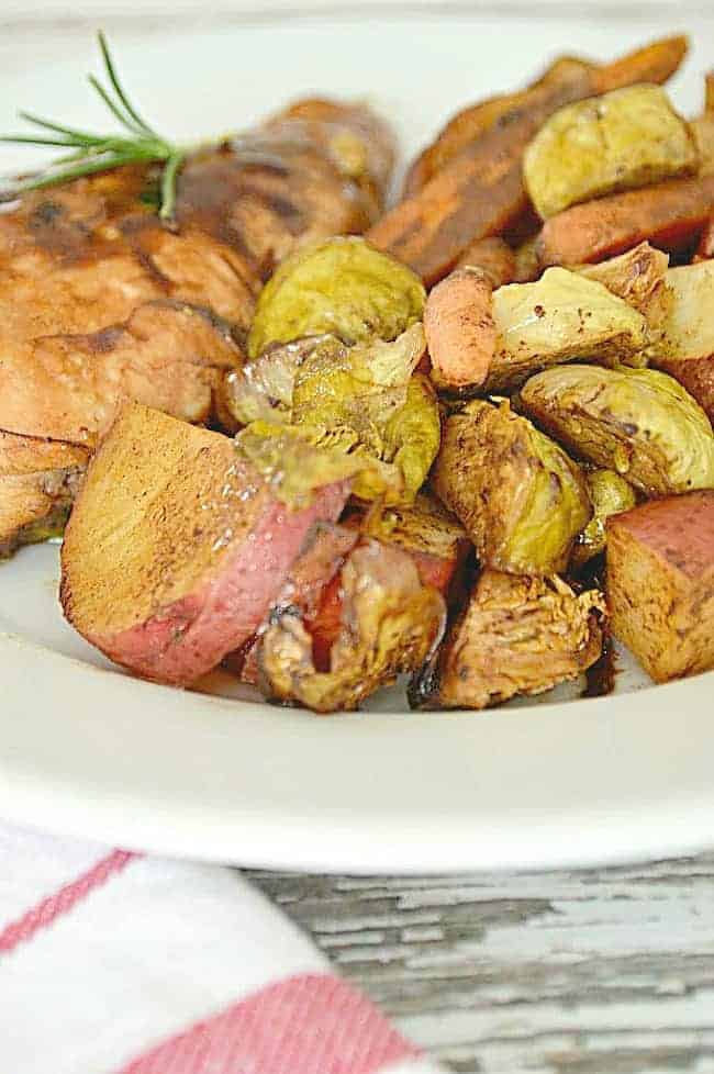 close up of one pan balsamic chicken and roasted vegetables on white plate