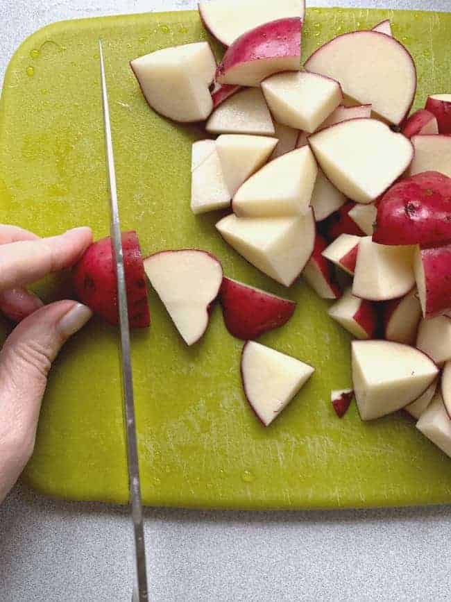 cutting up red potatoes for one pan balsamic chicken and roasted vegetables 