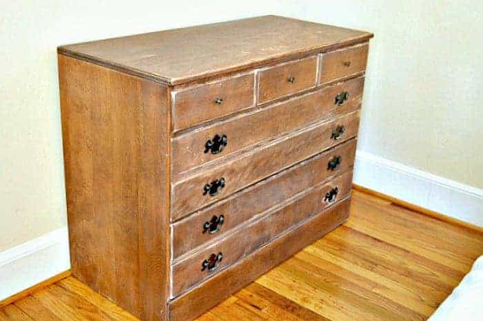 beat up old wooden dresser in corner of a bedroom