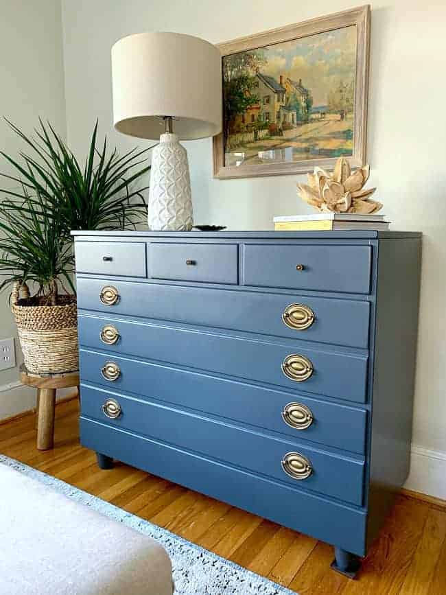 DIY dresser makeover in navy with white lamp and watercolor painting hanging above it