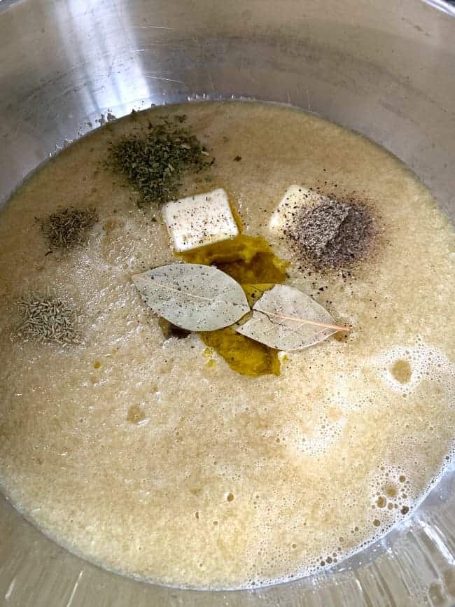 spices and butter sitting on top of chicken broth in pot 