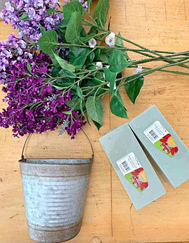 easy DIY spring wreath supplies laid our on a table, faux lilacs, rusty bucket and floral foam