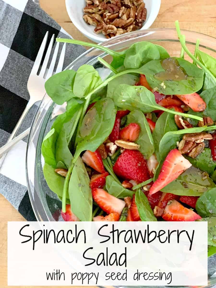 top view of spinach strawberry salad with a small bowl of chopped pecans next to it, plus a large graphic