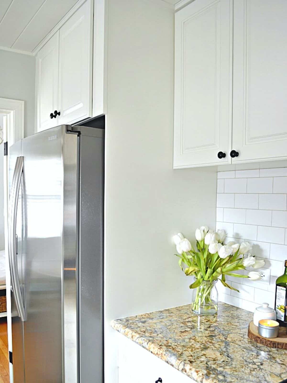 painted white cabinet built around stainless steel refrigerator