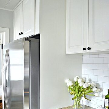 painted white cabinet built around stainless steel refrigerator