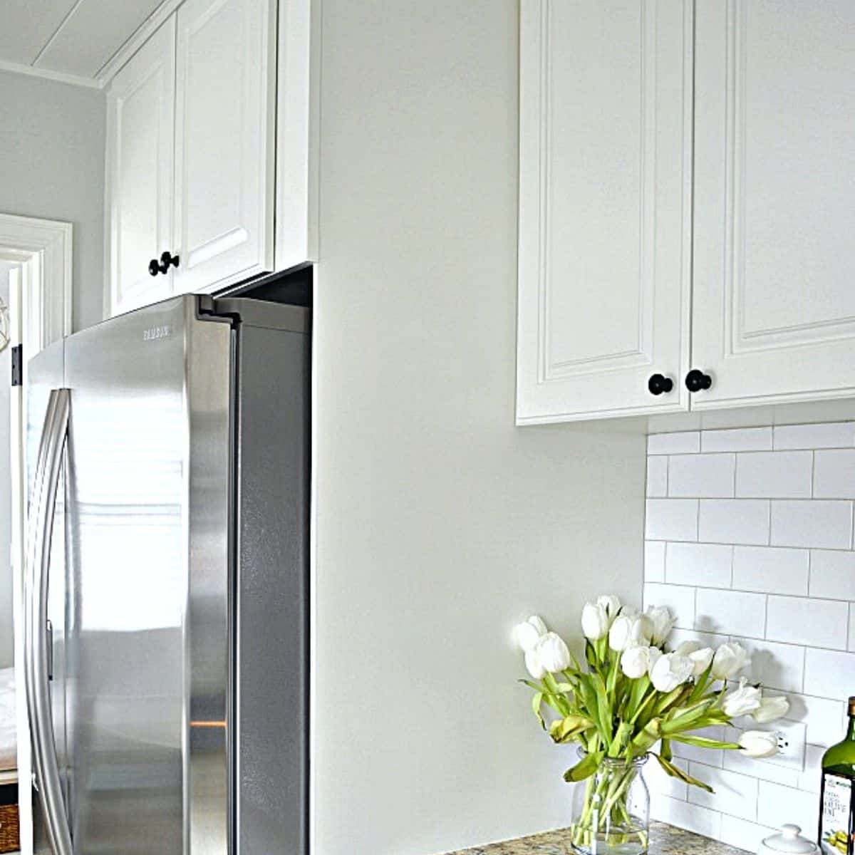 painted white cabinet built around stainless steel refrigerator