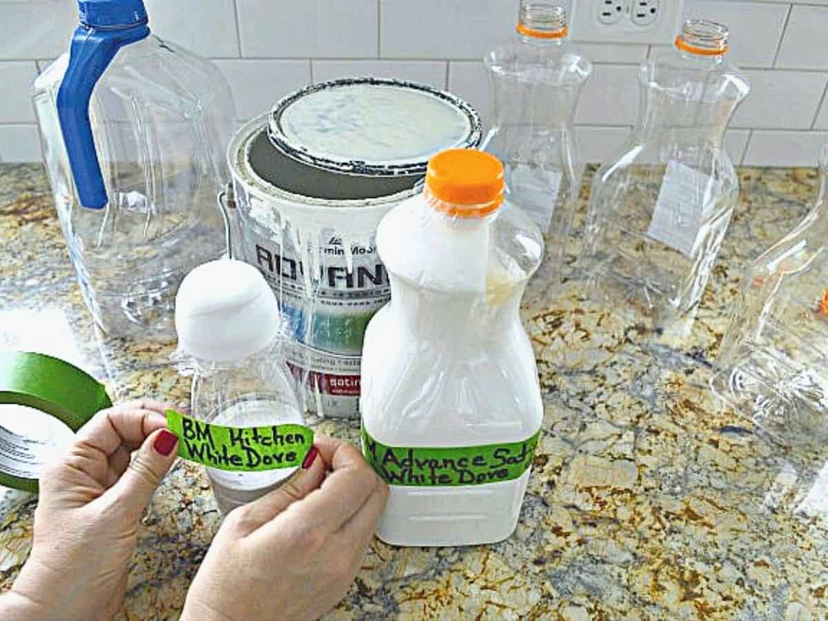 putting painter's tape labels on plastic juice containers filled with paint