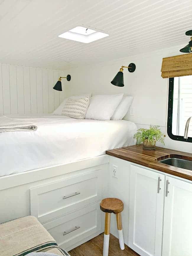 view of big white bed and kitchen cabinet in tiny RV 