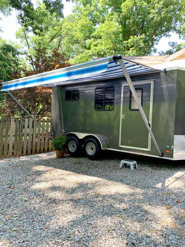 outside view of blue striped awning on dark gray landscape trailer turned RV 