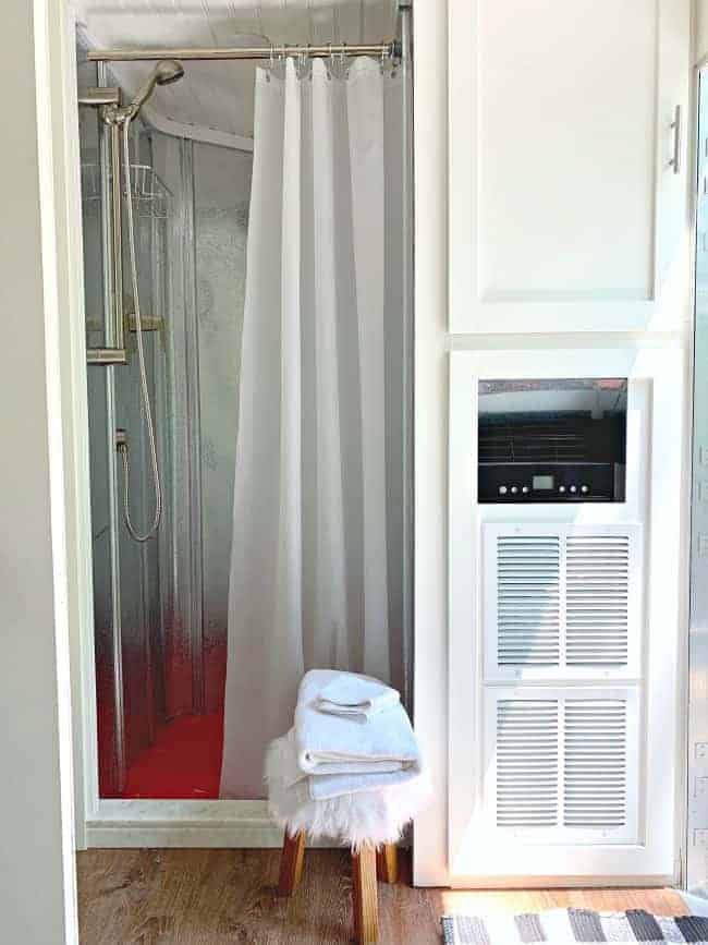 view of metal walls on shower, and shower curtain liner, along with a cabinet next to the shower