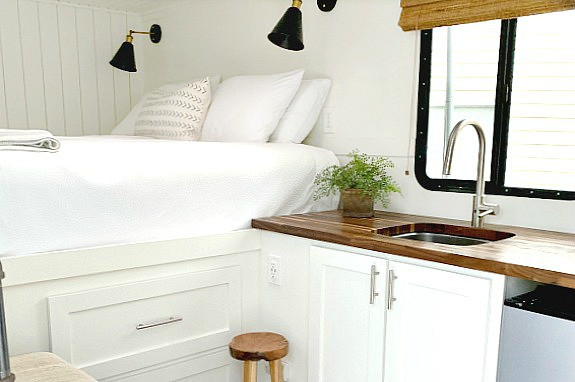 A kitchen with a sink and a bed in a cargo trailer conversion