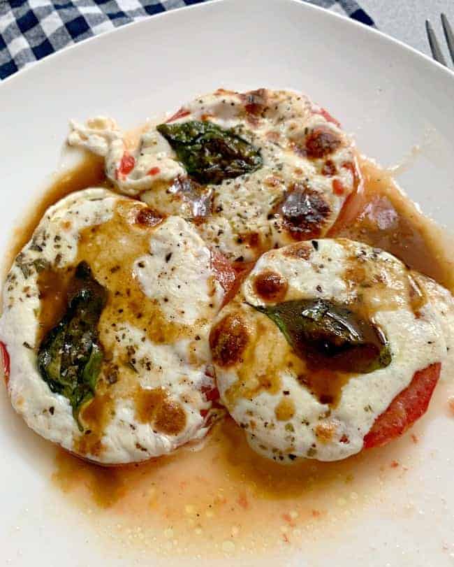 baked tomatoes and mozzarella on a white dish 