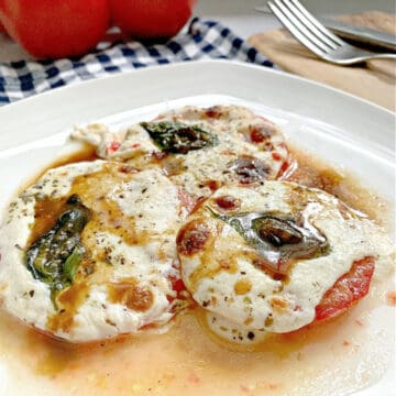3 slices of baked tomatoes with melted mozzarella and basil leaf