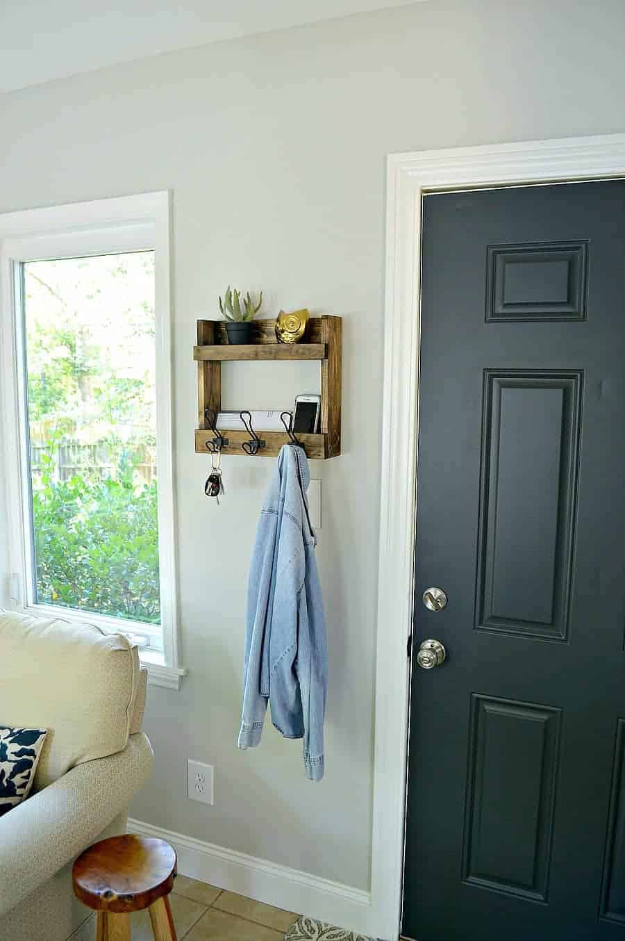 DIY coat rack with storage shelves hanging on wall next to dark gray door
